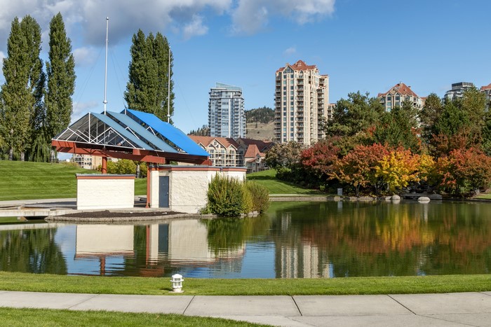 Park with pond and buildings in Kelowna, Canada during autumn