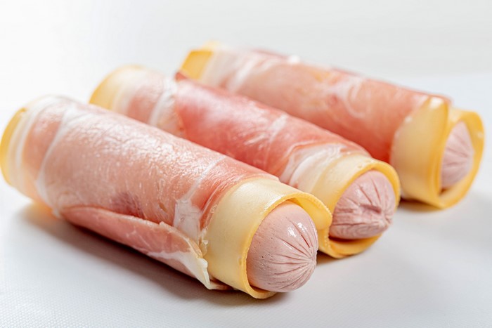 Three sausages wrapped in cheese and ham