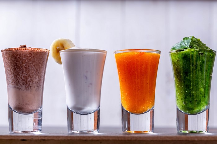 Four colorful smoothies in shot glasses