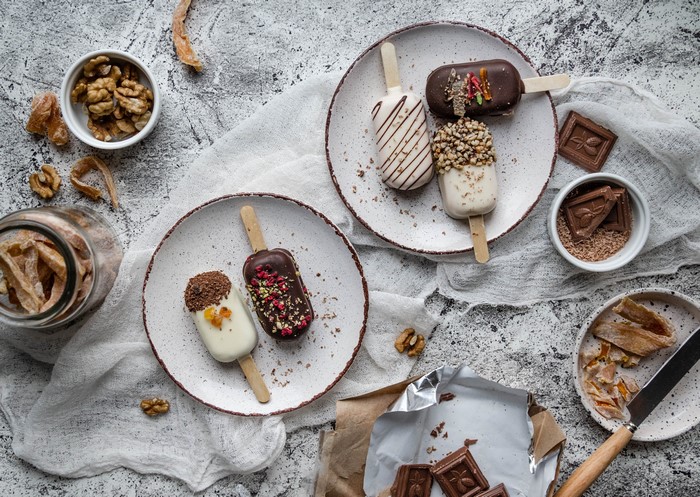 Ice cream bars with chocolate and nuts on plates