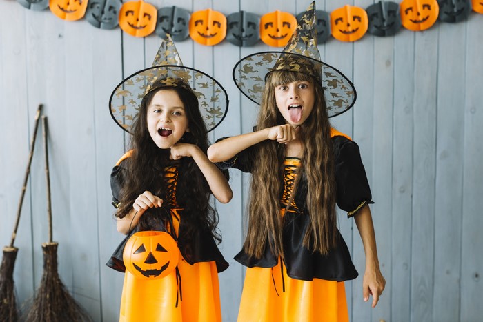 Two young girls in witch costumes with Halloween decorations