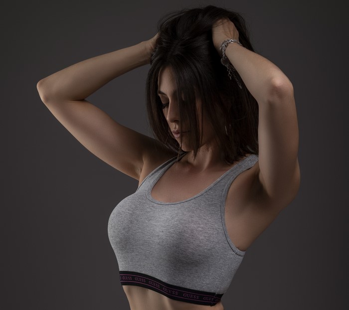 Woman in gray sports bra with hands in hair