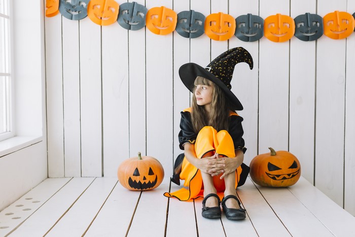 Little Girl in Witch Costume with Halloween Pumpkins