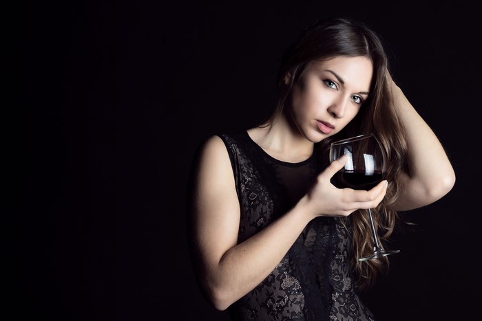 Woman in black dress holding a glass of red wine