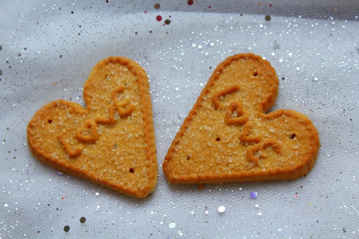 Two heart-shaped sugar cookies with the word "LOVE" embossed on them
