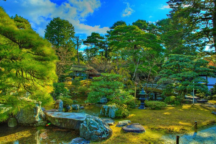 Japanese garden with pond, trees, and traditional building