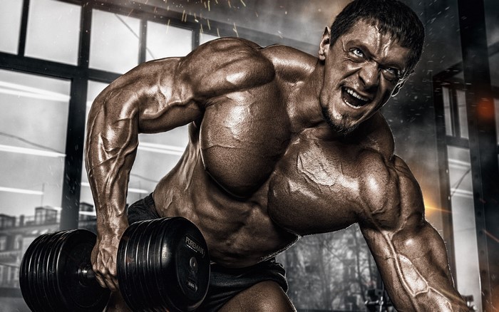 Muscular man lifting a dumbbell in a gym