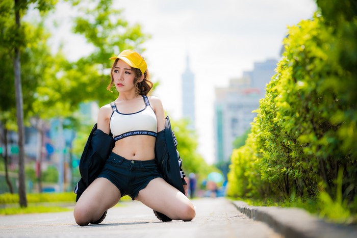 Asian woman in shorts and baseball cap posing