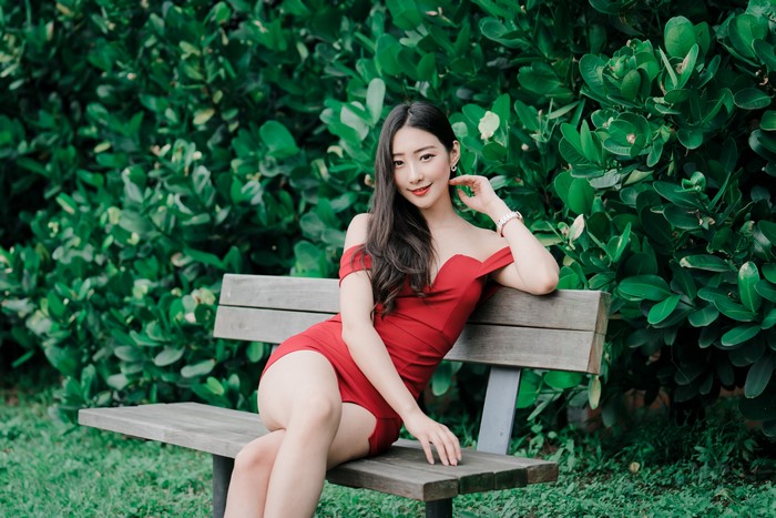 Woman in Red Dress Sitting on Bench with Smile