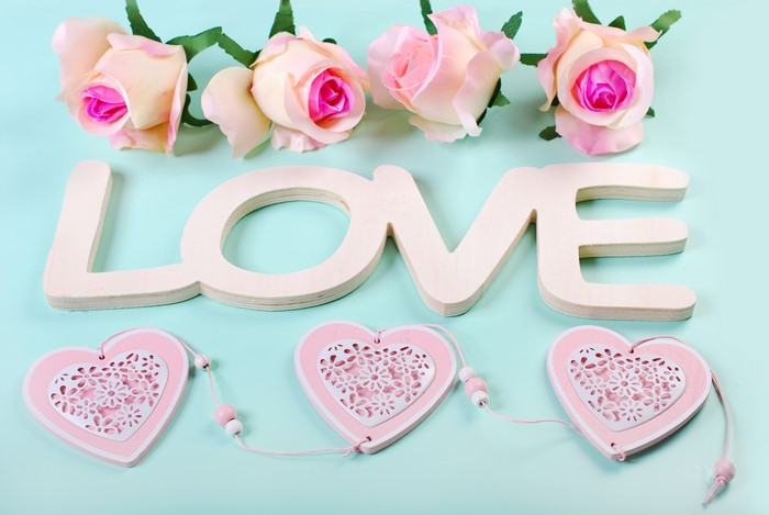 Four pink roses and wooden word LOVE with heart decorations