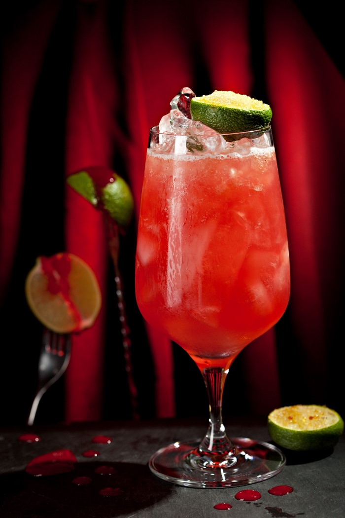 Red cocktail with lime and ice in a wine glass