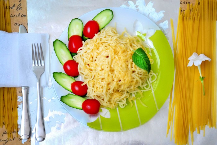 Spaghetti with tomatoes, cucumbers, cheese, and mint on a plate