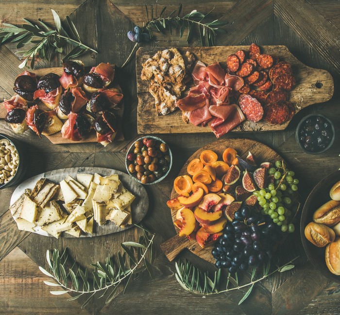 Charcuterie board with figs, prosciutto, cheese, fruit, and bread