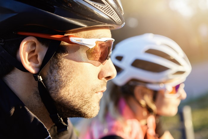 Two cyclists wearing helmets and sunglasses