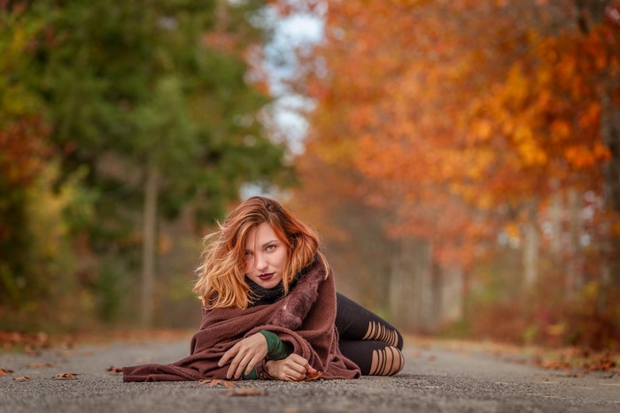 Redhead girl lying on a road in autumn