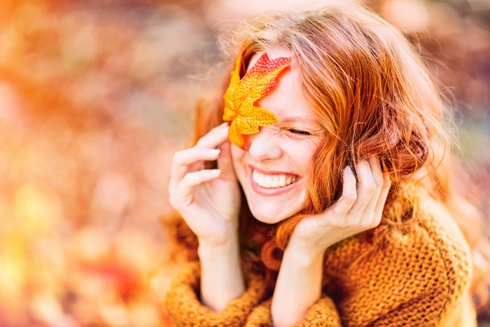Redhead girl with autumn leaf covering eye