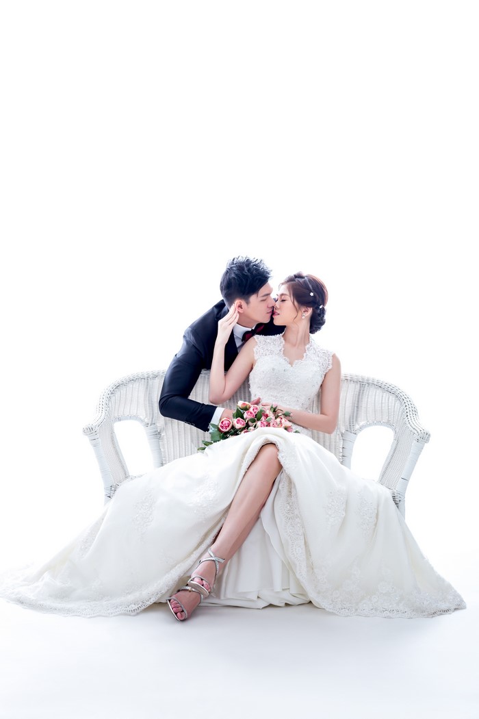 Bride and Groom Kissing on White Wicker Bench