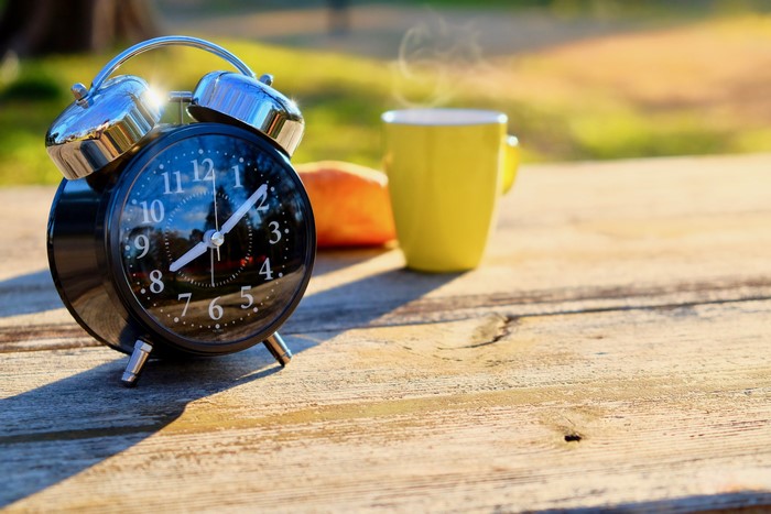 Alarm clock and coffee mug on a wooden table