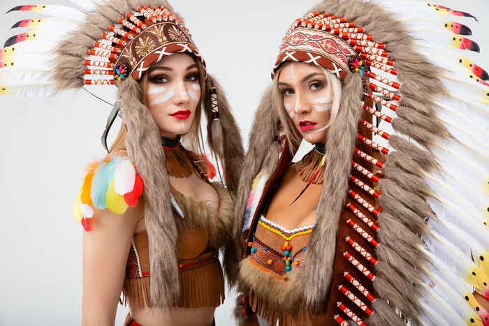 Two women in Native American headdresses and outfits