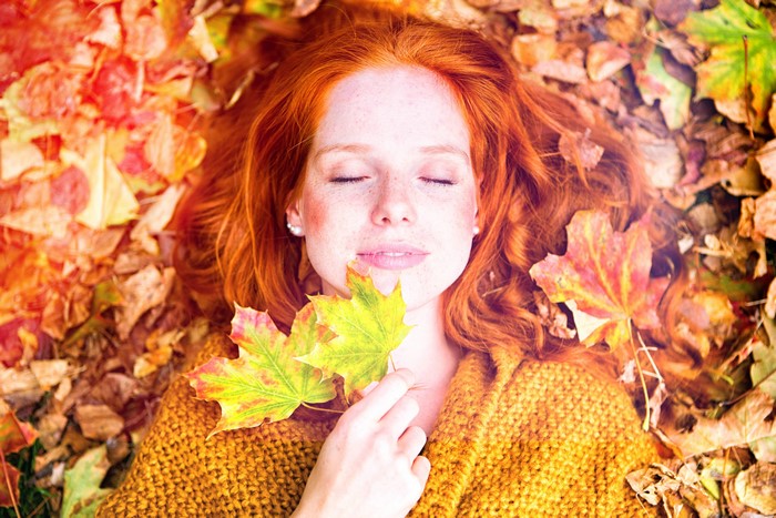 Redhead girl lying in autumn leaves