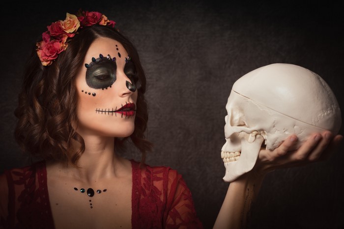 Woman with Day of the Dead makeup holding a skull