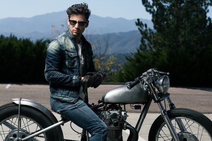 Man in denim jacket and jeans on a motorcycle
