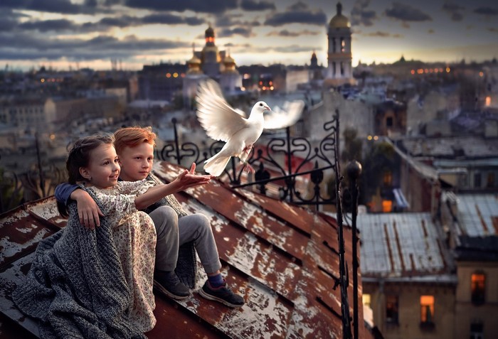 Children releasing a white dove on a rooftop at dusk