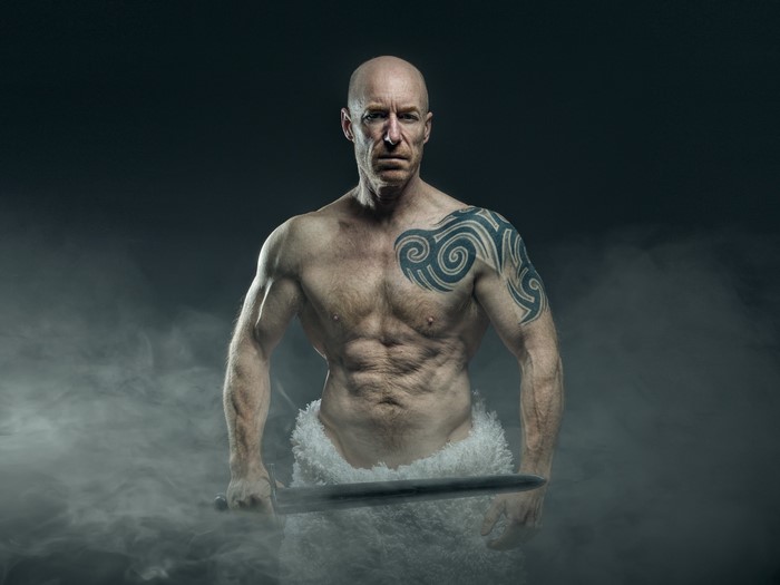 Bald man with tattoos holding a sword