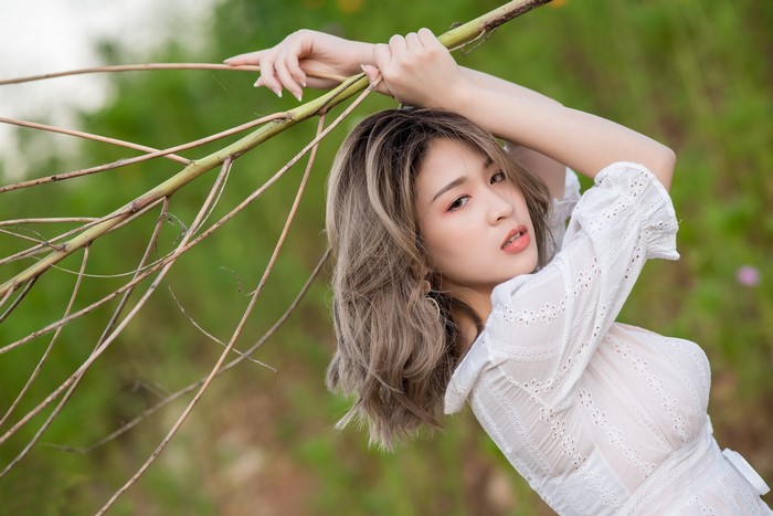 Woman Posing with Branches in White Dress