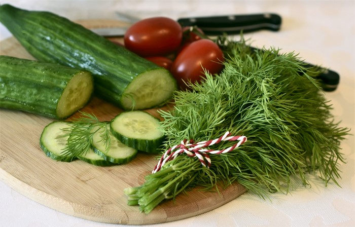 Cucumbers, Tomatoes, Dill, and Knives on a Cutting Board