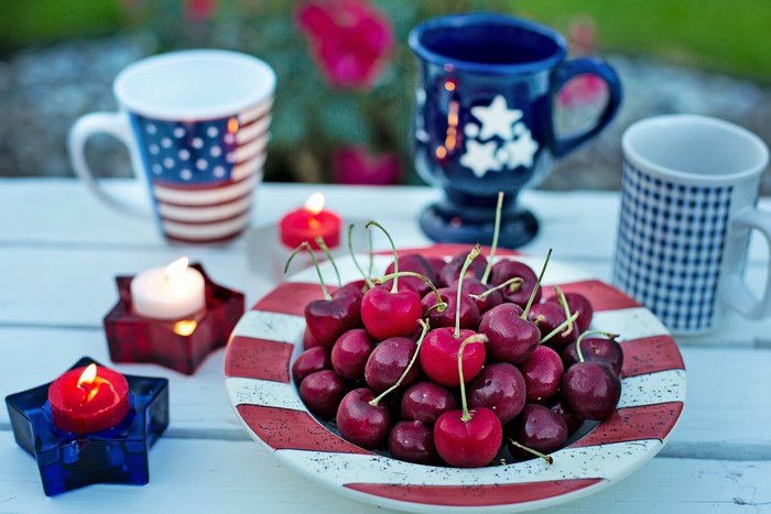 Cherries on a plate with American-themed mugs and candles