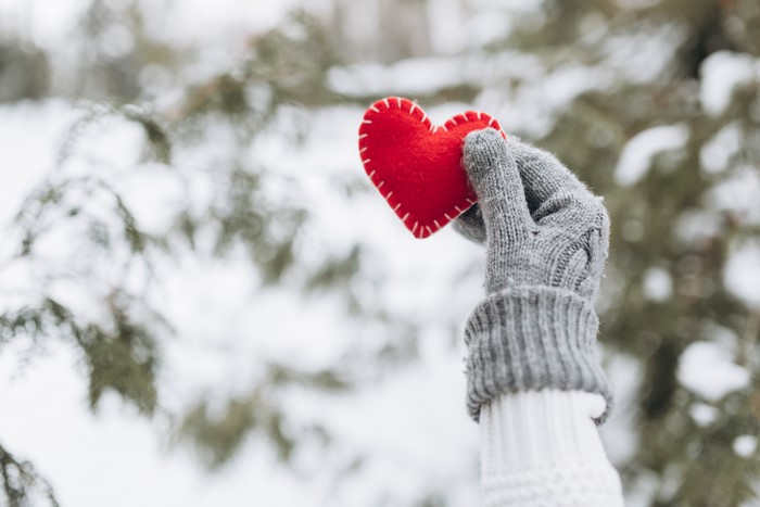 Hand holding a red heart in winter
