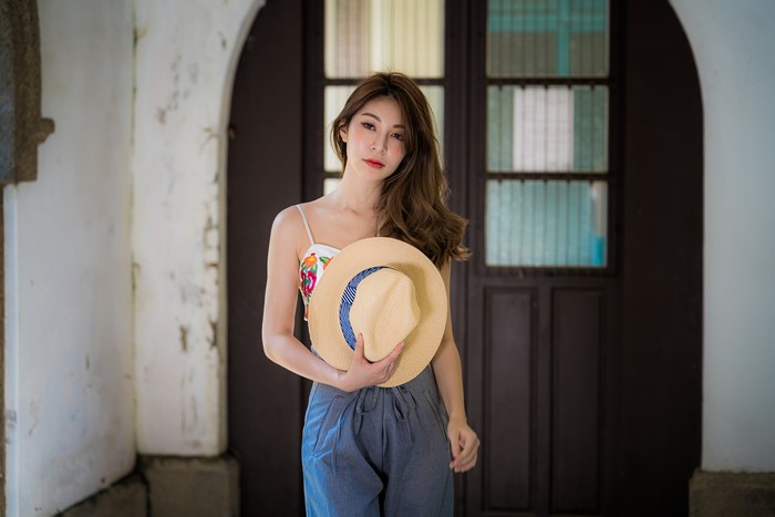 Asian woman with brown hair holding a hat
