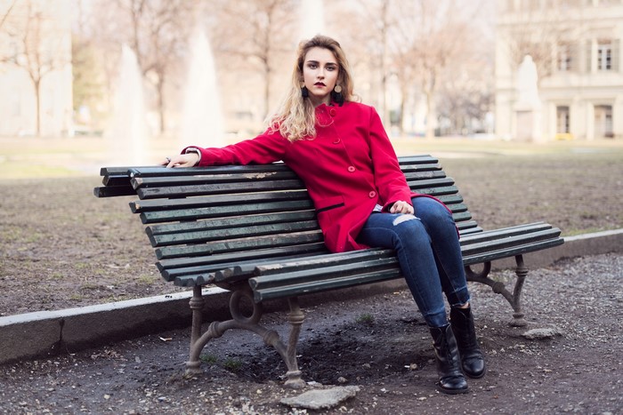 Woman in red coat sitting on a park bench