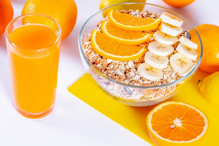 Muesli with orange and banana, orange juice, and oranges