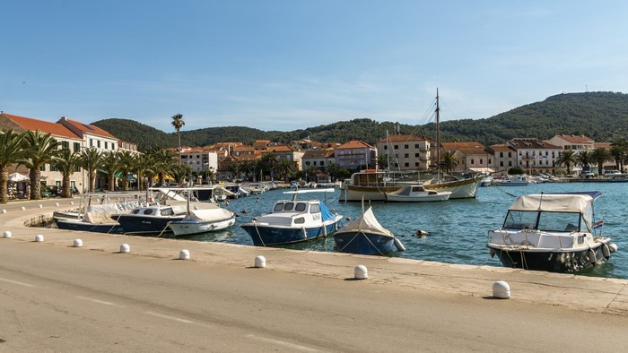 Boats docked in a harbor with buildings and hills in the background
