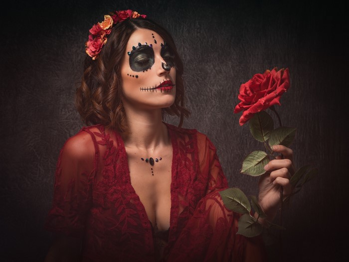 Woman with Day of the Dead makeup holding a rose