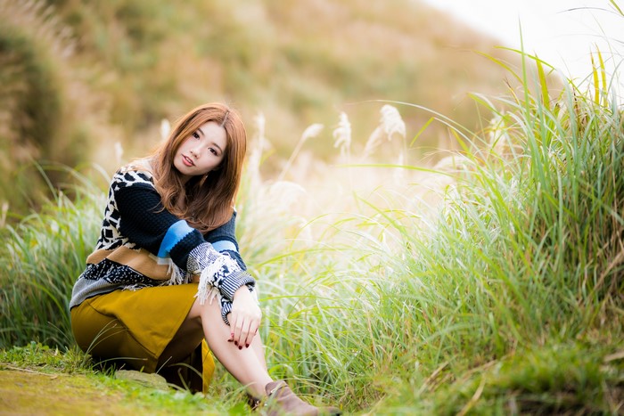 Asian woman with brown hair sitting in a field
