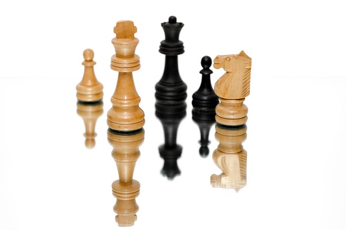 Chess pieces on a white background with reflection