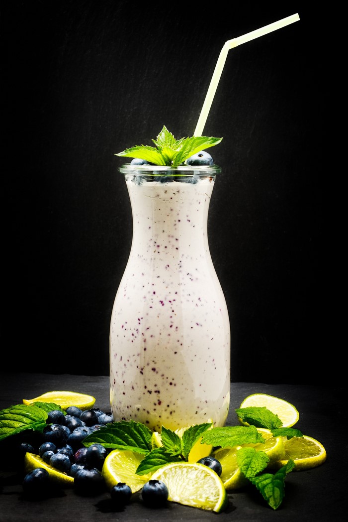 Blueberry lime smoothie in a bottle with mint and fruit