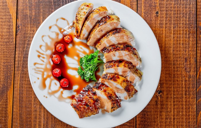 Sliced grilled chicken breast with cherry tomatoes and parsley