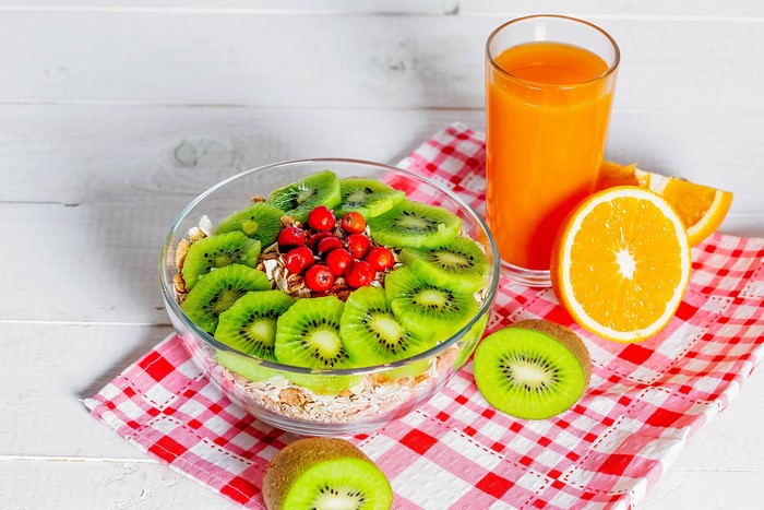Muesli with kiwi and berries, orange juice, and orange slices