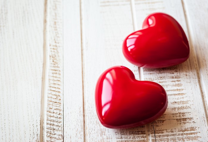 Two red hearts on a white wooden background
