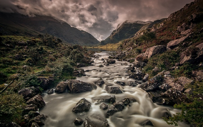 River flowing through a rocky mountain valley under cloudy skies
