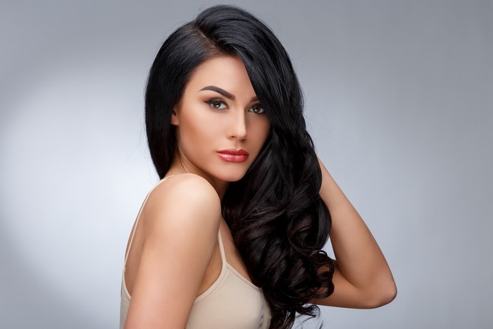 Brunette girl with wavy hair on gray background