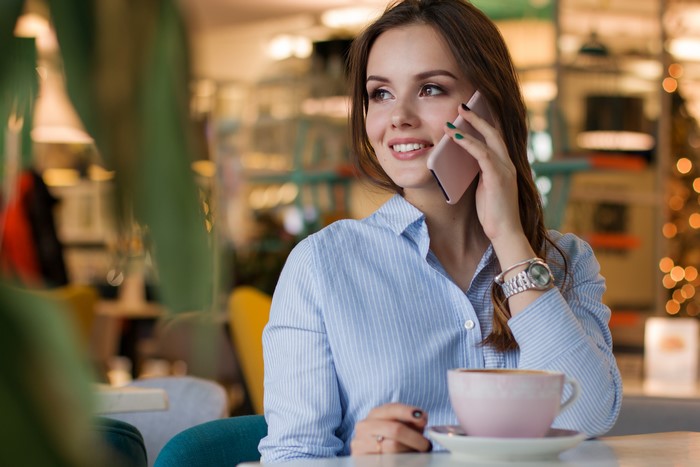 Woman talking on smartphone in cafe with coffee
