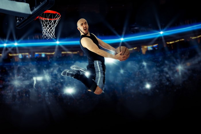 Man jumping with basketball in arena