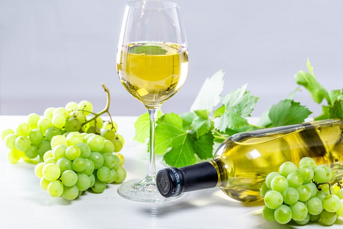 White wine bottle and glass with green grapes