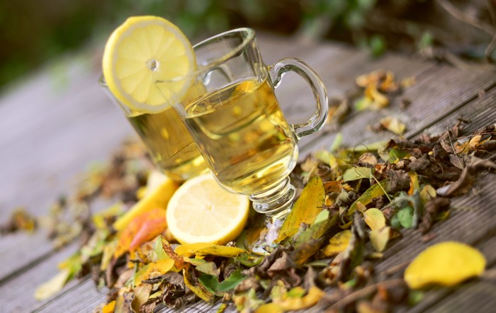 Autumn tea with lemon and fallen leaves