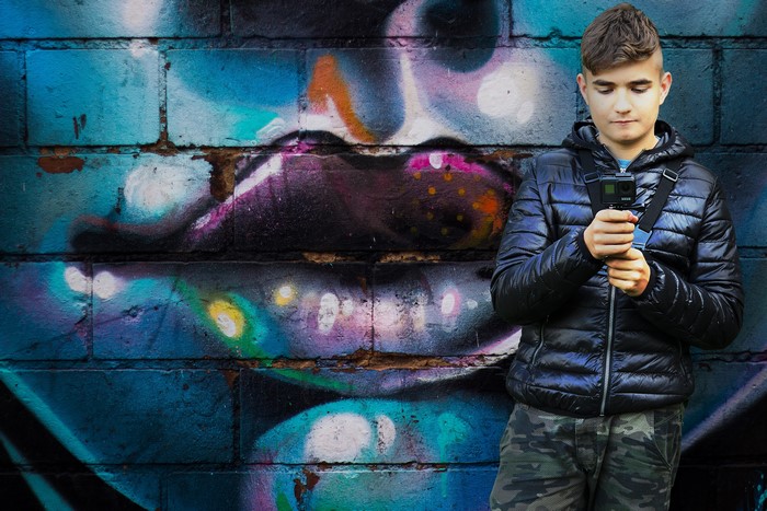 Boy with GoPro in front of graffiti wall